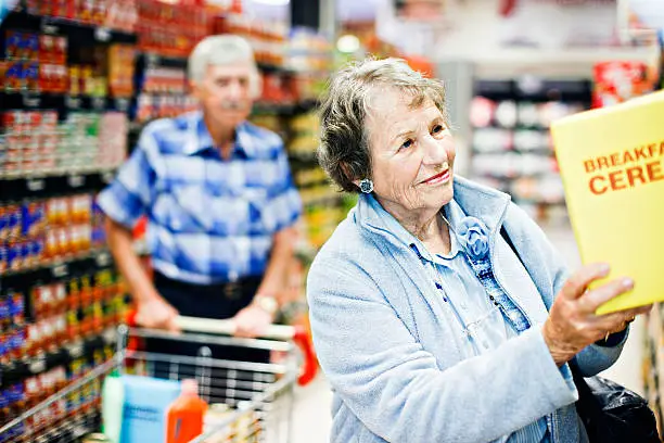 Photo of Senior couple smile on finding favourite cereal in supermarket