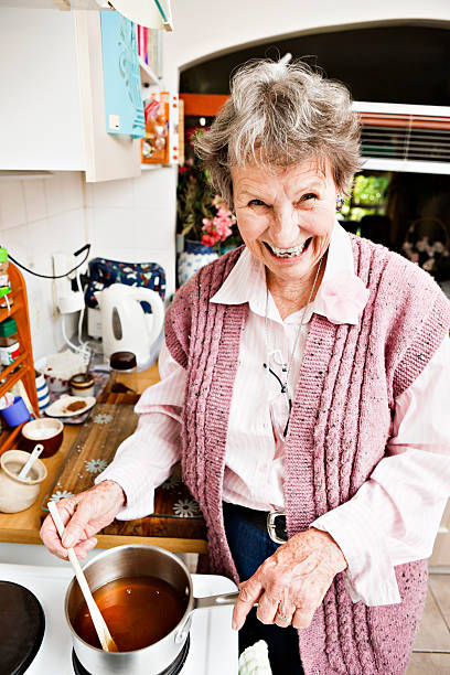 istock Happy old lady stirs a pan on the stove 156894226
