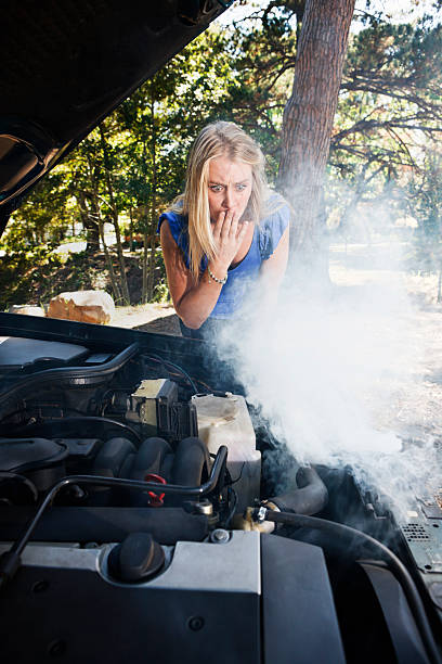 istock Beautiful blonde looks in horror at her smoking car engine 156894631