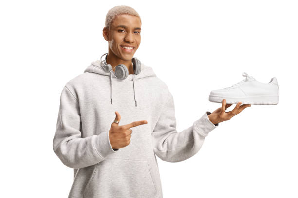 istock Cool african american guy holding a white sneakers and pointing 1568956960