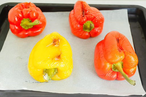 Large red and yellow peppers baked in the oven on a baking sheet. Ingredients for salad. Concept Traditional Italian dish. Vegetarian and vegan food. Horizontal orientation.