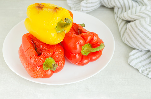 Large red and yellow peppers baked in the oven on a white plate. Ingredients for salad. Concept Traditional Italian dish. Vegetarian and vegan food. Horizontal orientation.