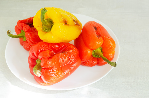 Large red and yellow peppers baked in the oven on a white plate. Ingredients for salad. Concept Traditional Italian dish. Vegetarian and vegan food. Horizontal orientation.