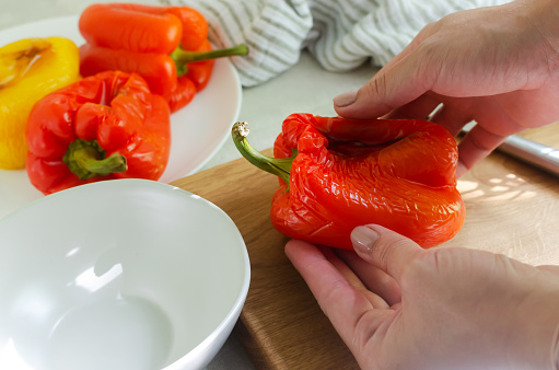 The process of preparing a salad with large red and yellow roasted peppers. Concept Traditional Italian dish. Vegetarian and vegan food. Horizontal orientation.