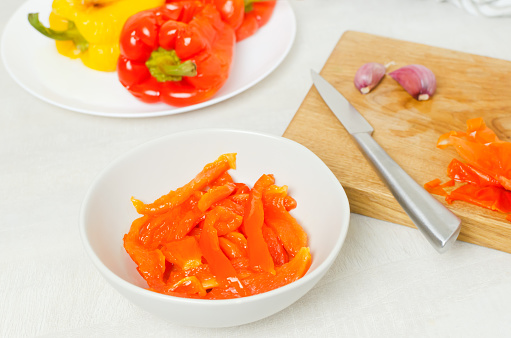 The process of preparing a salad with large red and yellow roasted peppers. Concept Traditional Italian dish. Vegetarian and vegan food. Horizontal orientation.