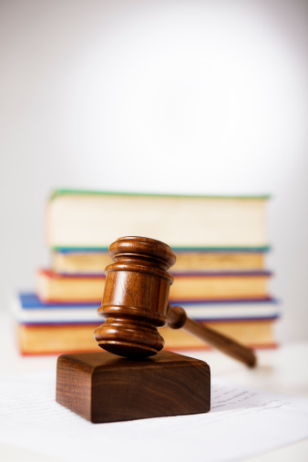 A wooden gavel occupies the foreground with a pile of out-of-focus law books behind it. Law and justice happening here!