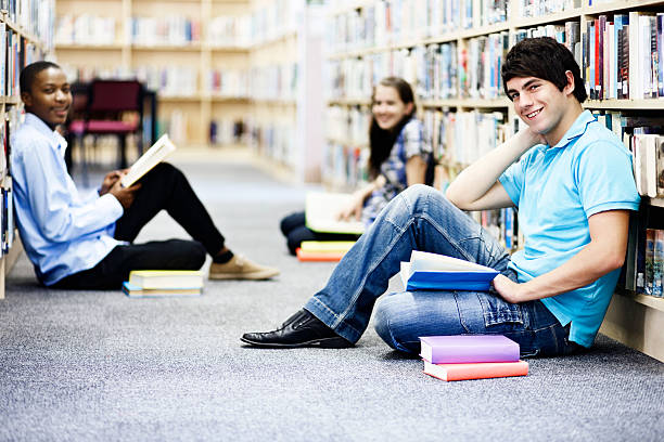 istock Three cheerful students smile up from their studies in library 156896939