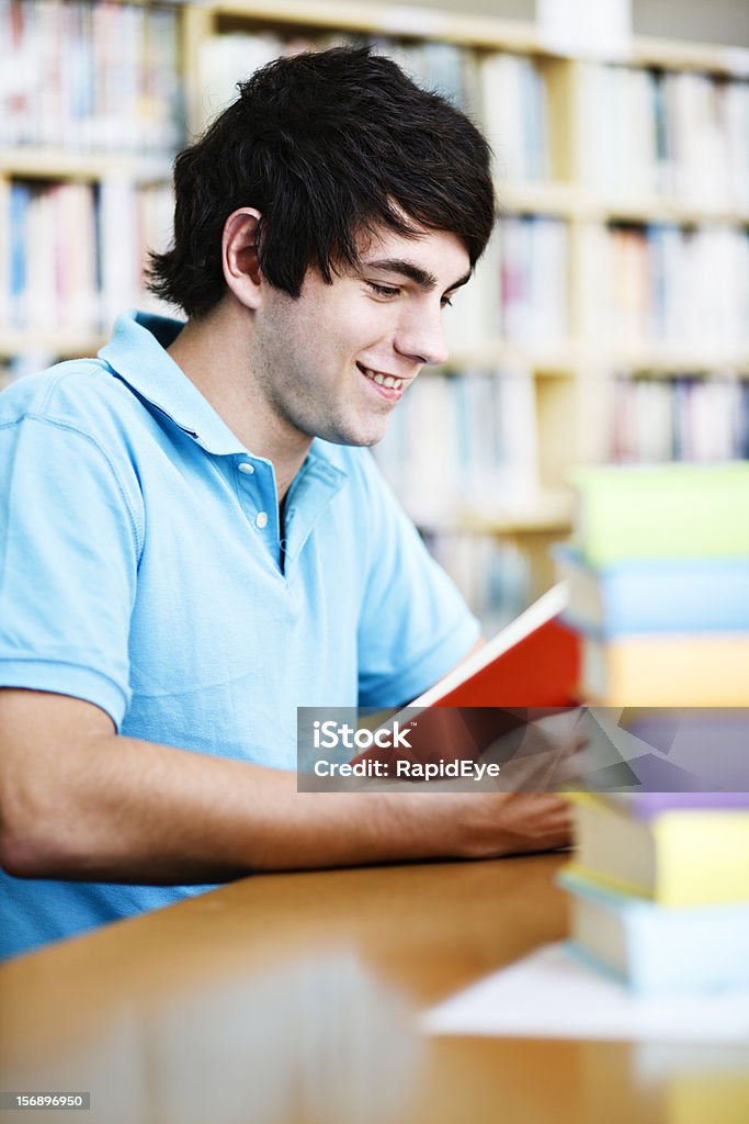 Atractivo joven estudiante sonrisas como él estudios de la biblioteca - Foto de stock de 20 a 29 años libre de derechos