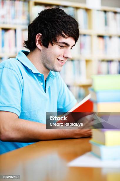 Atractivo Joven Estudiante Sonrisas Como Él Estudios De La Biblioteca Foto de stock y más banco de imágenes de 20 a 29 años