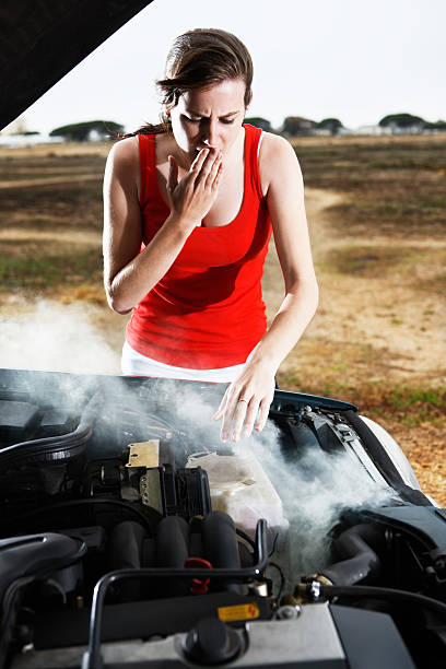 Pretty brunette examining stranded car's smoking engine worriedly