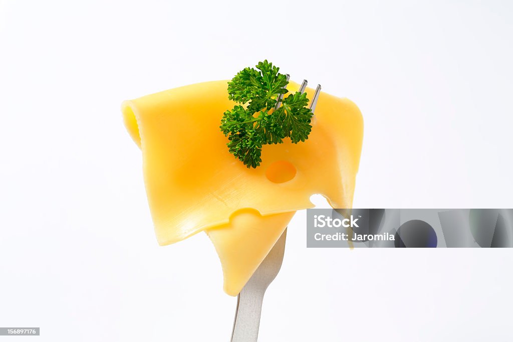 slice of cheese on a fork thin slice of fresh cheese with a parsley on a metal fork Cheese Stock Photo