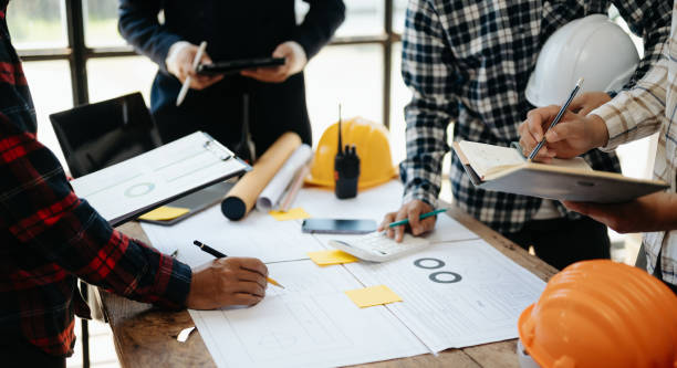 istock Engineer desk with object paper and tablet with blurry engineer teamwork hardworking to consults about their building project. 1568985186