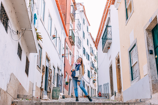 girl posing between buildings on a narrow street in Lisbon. look at camera.