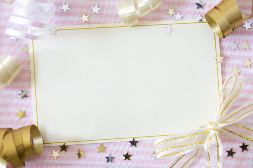 A blank card with a gold border,  with gold and cream ribbons, and stars.