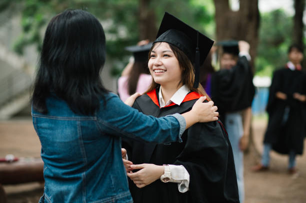 I am proud of you. Portrait of happy Chinese student wearing graduation gown hugging parents. Achieve Family Goals stock pictures, royalty-free photos & images