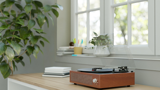 Close-up image of a vintage record player on a wooden table against the window in a minimalist white room. 3d render, 3d illustration