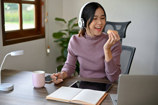 Beautiful Asian girl eating a donut while studying at her study table in her house
