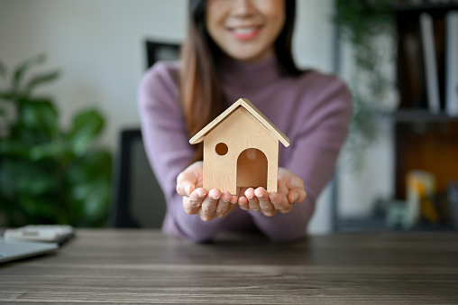 Home investment concept, young Asian girl with house model planning on buying her house