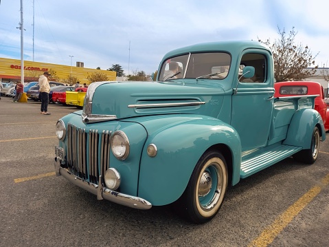 Buenos Aires, Argentina – June 05, 2023: An old aqua 1940s Ford pickup truck in a parking lot at a classic car show
