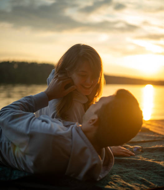 istock Romantic couple relaxing on the sand by a lake. Enjoying each other vertical image 1569052011