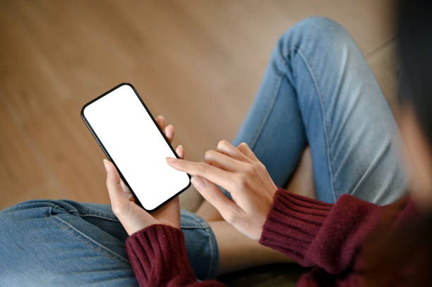 istock A girl using blank screen mock up smartphone while sitting in the sofa 1569053075