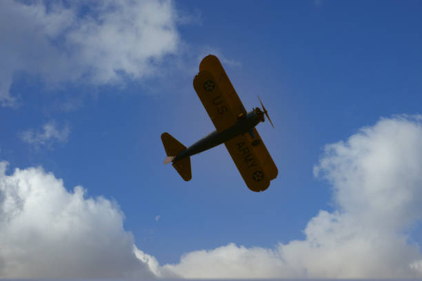 Vintage propeller biplane flying against a bright blue sky