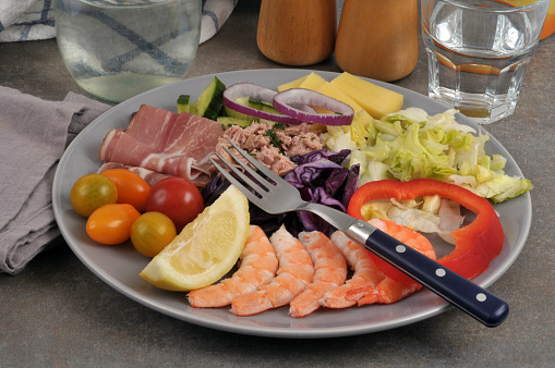 Mixed salad served on a plate with vegetables, raw ham and prawns