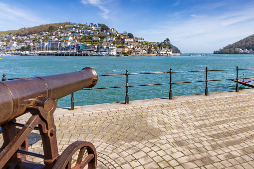 An old Crimean cannon sat on the side of the river Dart in Dartmouth with Kingswear in the background.