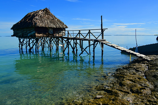 Taborio, Eita motu, South Tarawa Atoll, Gilbert Island, Kiribati: rustic thatched roof bungalow on stilts and ramshackle access bridge - horizon on the Tarawa lagoon - traditional architecture of Kiribati.