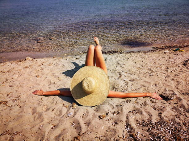 istock Mature woman lying on a sand beach 1569121479