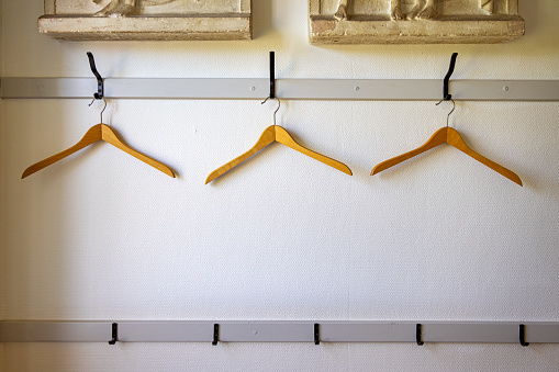 Three empty coat hangers on a coat rack in a corridor