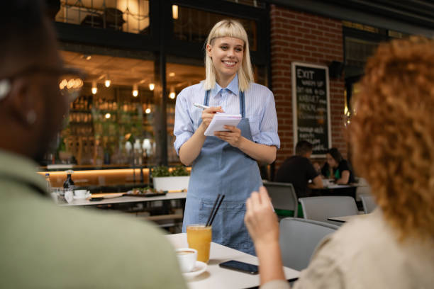 istock Happy waitress writing her customers' orders in a restaurant. 1569148003