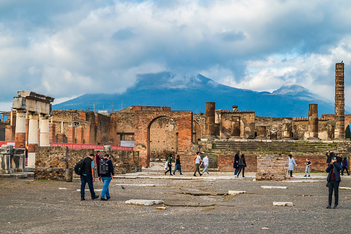 Pompeii, Italy - 27th Dec 2022: Temple of Giove, ancient stone temple now in ruins with columns & part of a Jupiter statue. Mount Vesuvius in the distance
