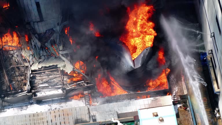 Aerial view of Fire in industrial building. Multi-storey concrete hangar with flames.