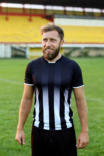 Smiling soccer player posing on a field. About 30 years old, Caucasian male.