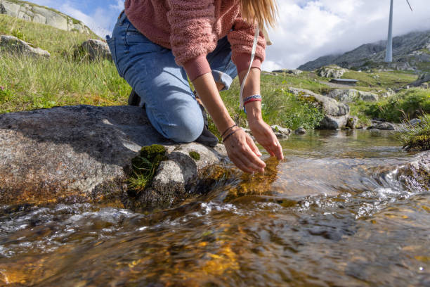 istock Woman on a hike drinking fresh water from a stream 1569184667