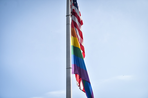 LGBTQIA flag and United States of America flags seen together hoisted on a pole