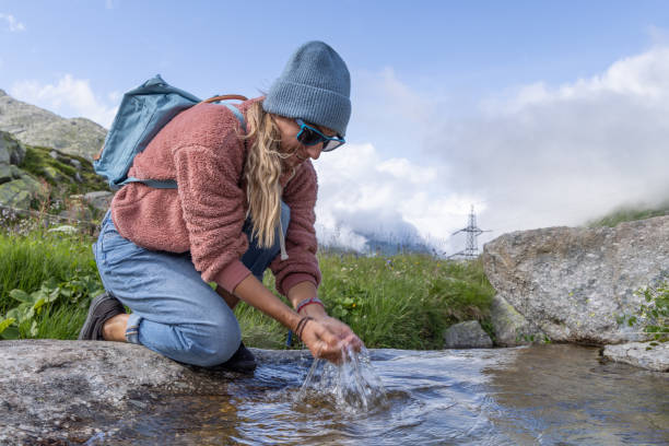 istock Woman on a hike drinking fresh water from a stream 1569184719