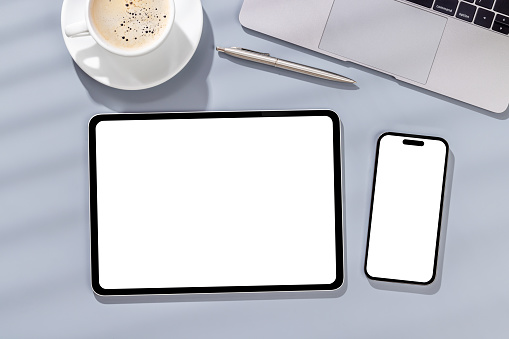 Blank white screen smartphone and tablet on a desk, perfect for your design mockup