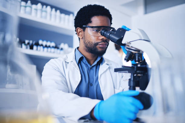 istock Microscope, science and black man working on study in laboratory for medical research analysis. Scientist, microbiology and biotechnology worker check investigation, innovation and dna pathology test 1569219303