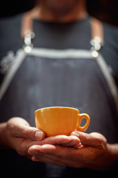 man holding with both hands orange cup of coffee. copy space