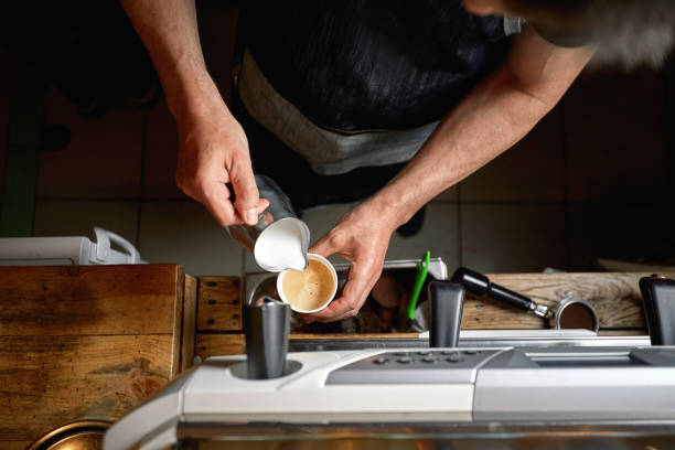 Top view of Caucasian man pouring milk in a cup of coffee