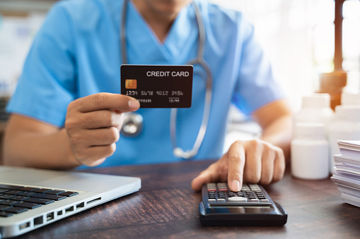 Doctor hold credit cards, conduct financial transactions via tablets and data documents, put on the desk in the morning.