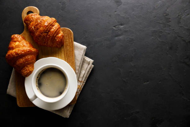 istock Black coffee with croissants on dark background. 1569229127