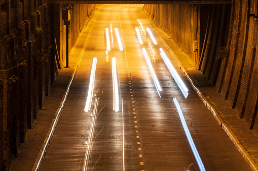 A group of cars and its white front lights, passing, by night, through the Arturo Illia Tunnel, in the Rosario city, Santa Fe province, Argentina. Long exposition photo,  On day: July 10, 2003.