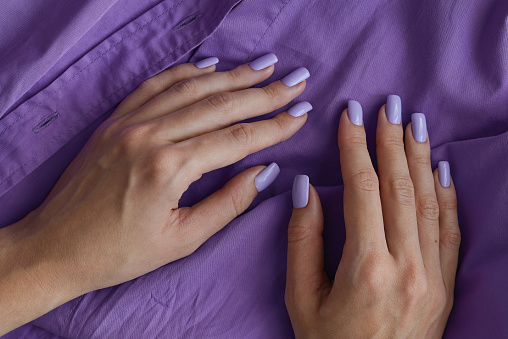 Manos femeninas con manicura gelish y uñas de color púrpura. Uñas lavanda. Esmalte de uñas permanente photo