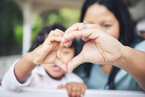 Mother, child and heart hands for love, care or compassion together in the outdoors. Mom and little kid putting hand for loving emoji, like or sign gesture for support, trust or parenting outside