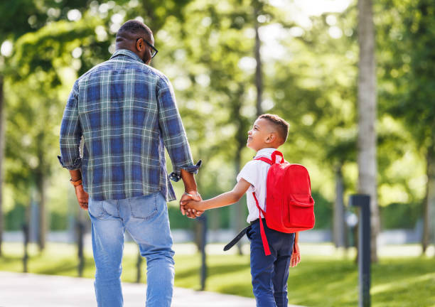 istock Schoolboy looking at father with smile while going with dad to first grade in school on sunny autumn day 1569230192