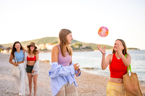 Group of young girls walking and having fun on the empty beach of Primosten early in the morning.