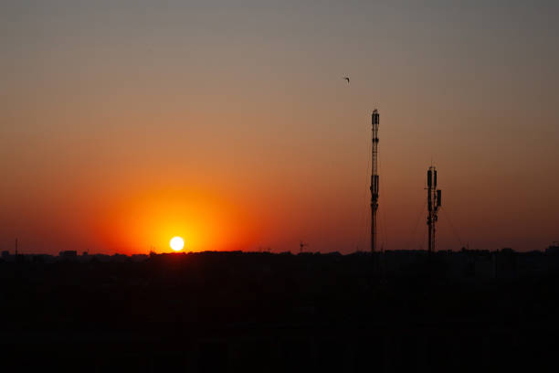 istock 5G Communication tower or 4G network telephone cellsite silhouette on sunny colorful sky background. 1569233435